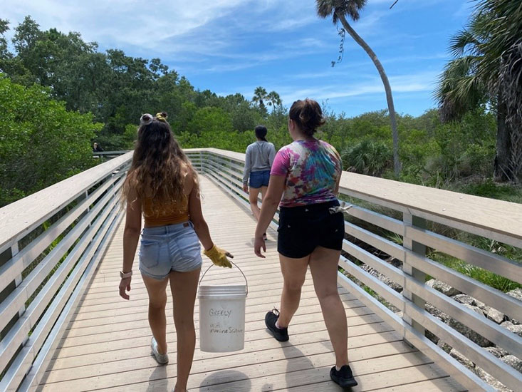 Campers Alana, Savannah, and Sophie walking along the paths through the mangroves to find trash.