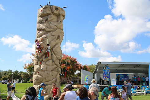 Young climbers take on the rock wall in the foreground of the Poynter Park Stage at the 2018 St. Petersburg Science Festival 