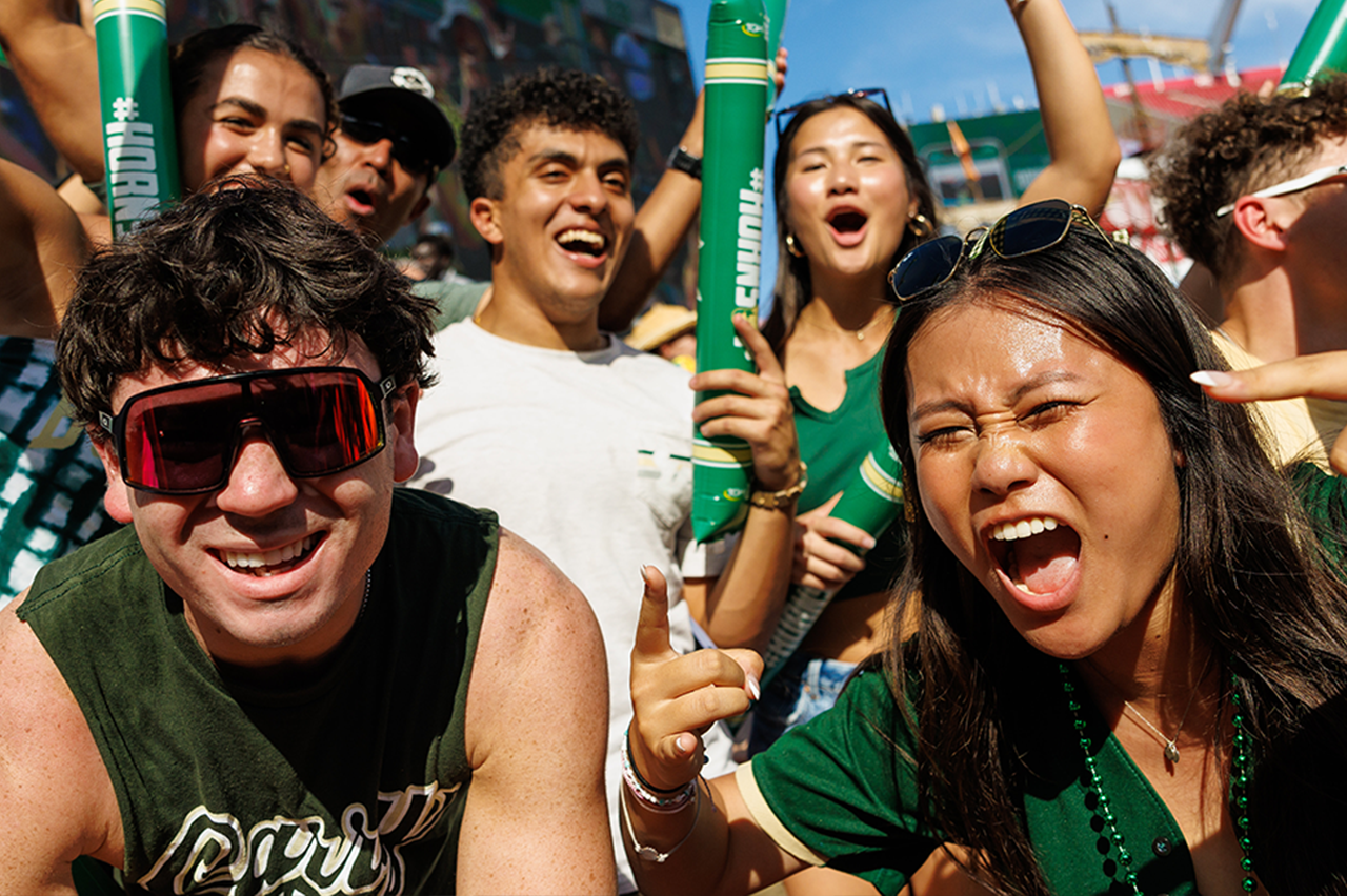 Students in USF merchandise cheer at a football game
