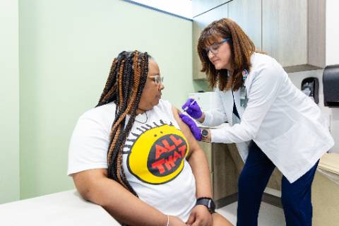 a woman gets an immunization shot from a medical professional