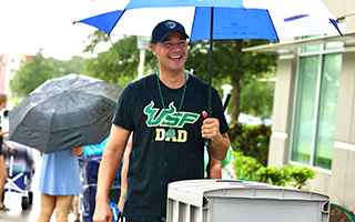 father with umbrella at move in