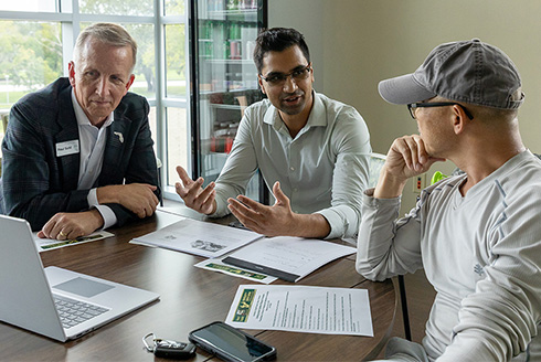 Three men sit at table