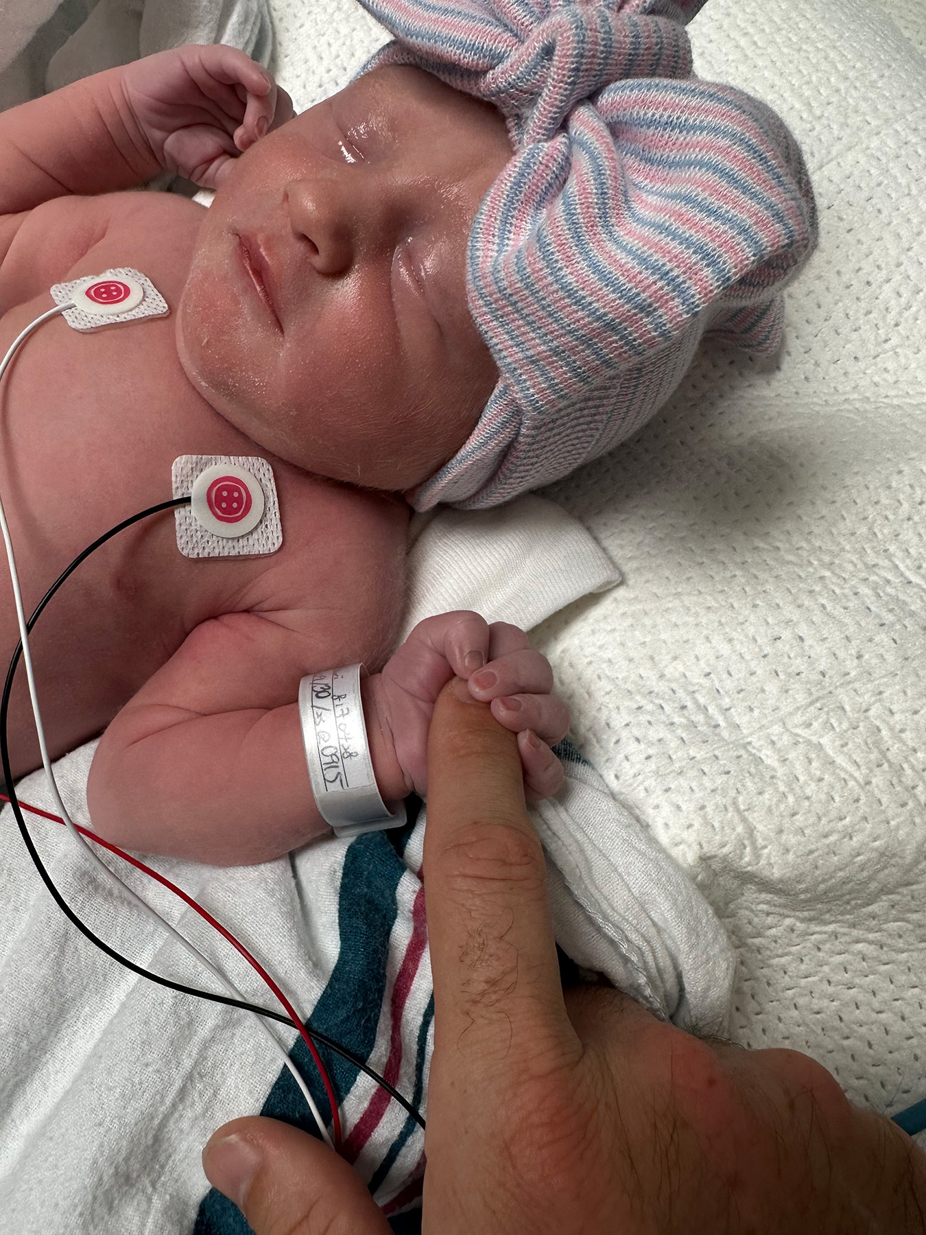 Womack baby holding dad's finger