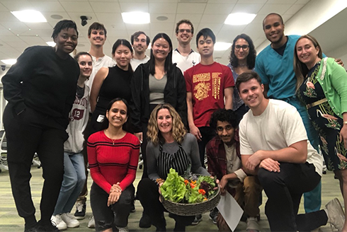 Group poses with bowl of vegetables