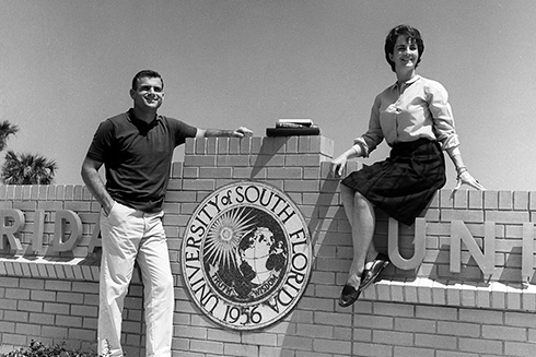 Two people sit near USF signage in the 1960s