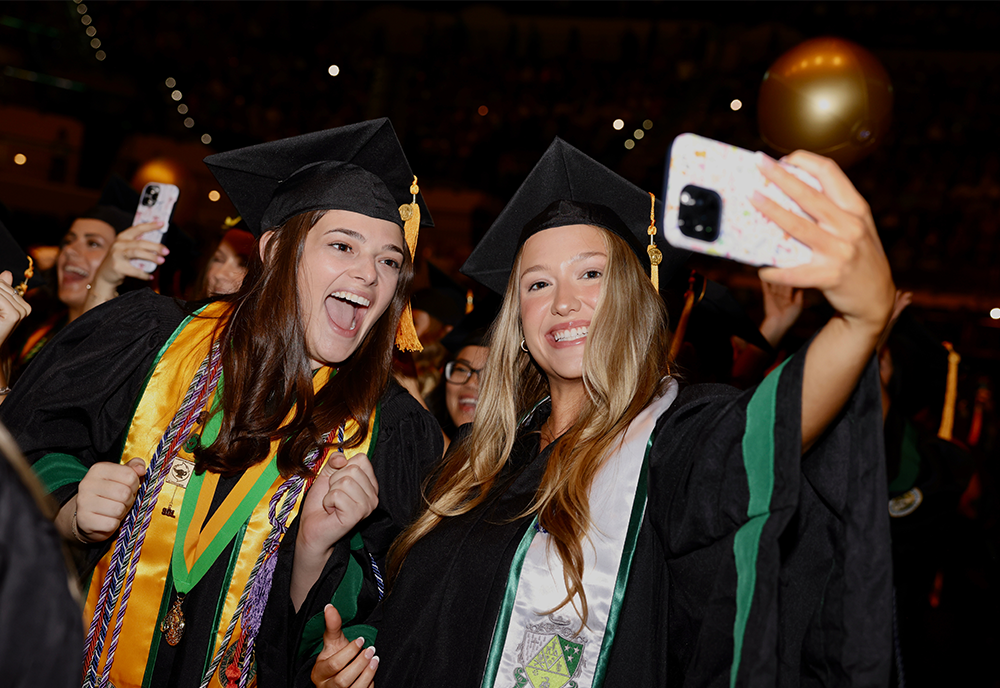 Two students smile for a selfie at USF commencement