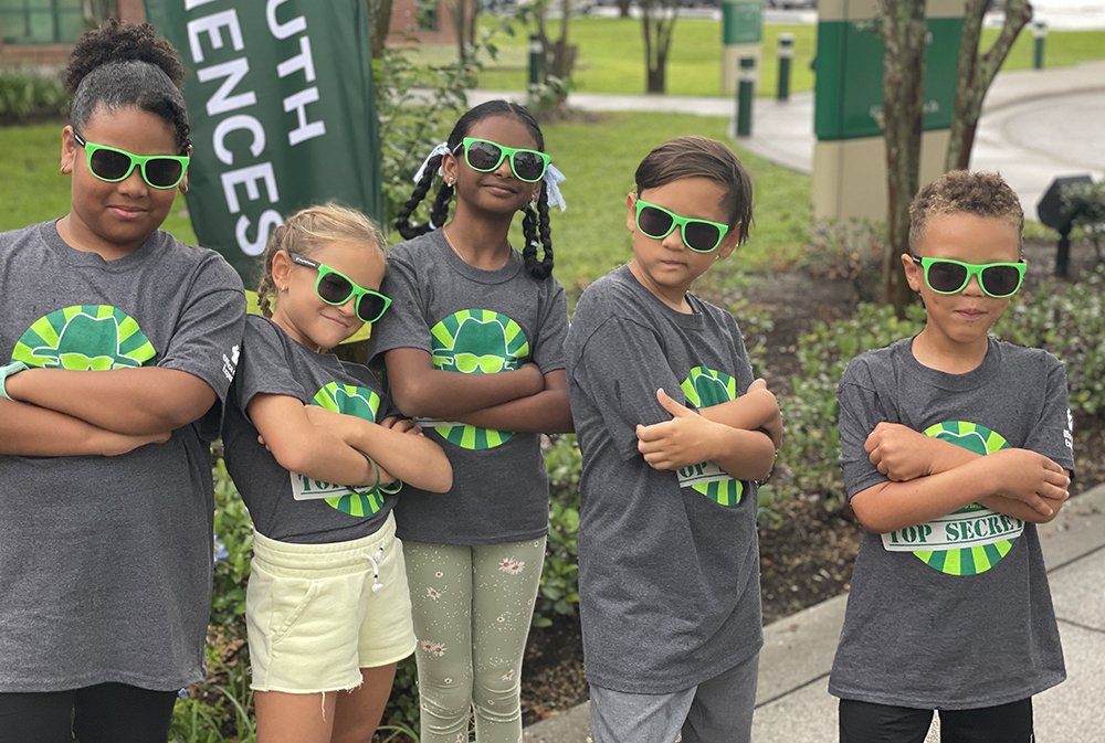 Young students wear sunglasses with their arms crossed