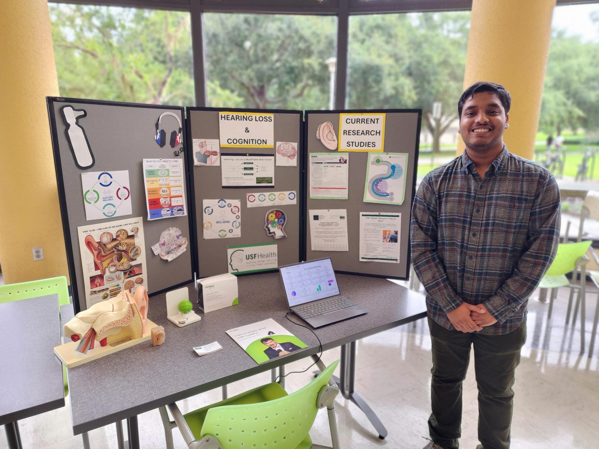 student standing with poster board on hearing loss