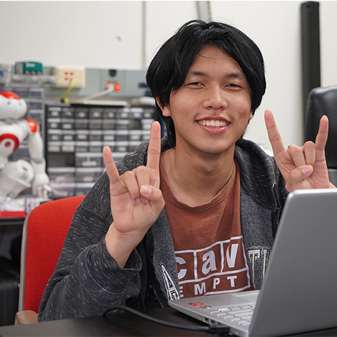 USF student throwing up bulls sign with robot behind him