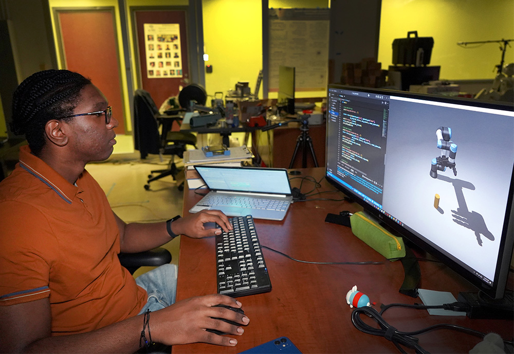 Denilo at a computer examining his robot on the screen