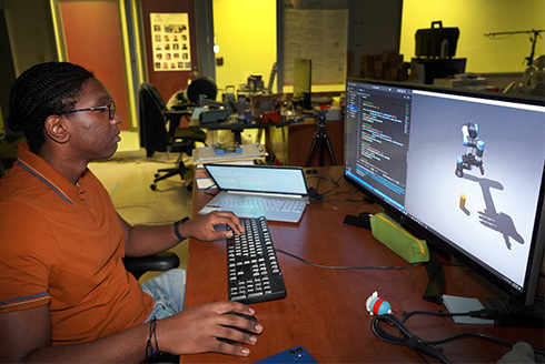 Denilo at a computer examining his robot on the screen