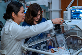 Two physicians stand near baby in the NICU