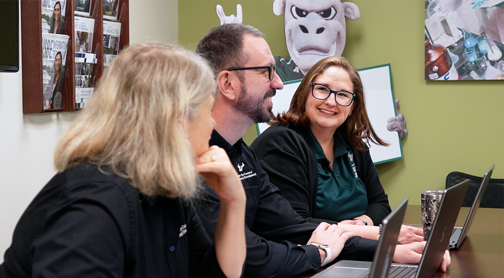 Three USF employees sit at their computers