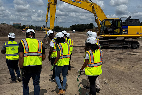 Students walk the construction site of the on-campus stadium