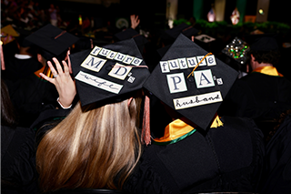 Two students show off their commencement caps