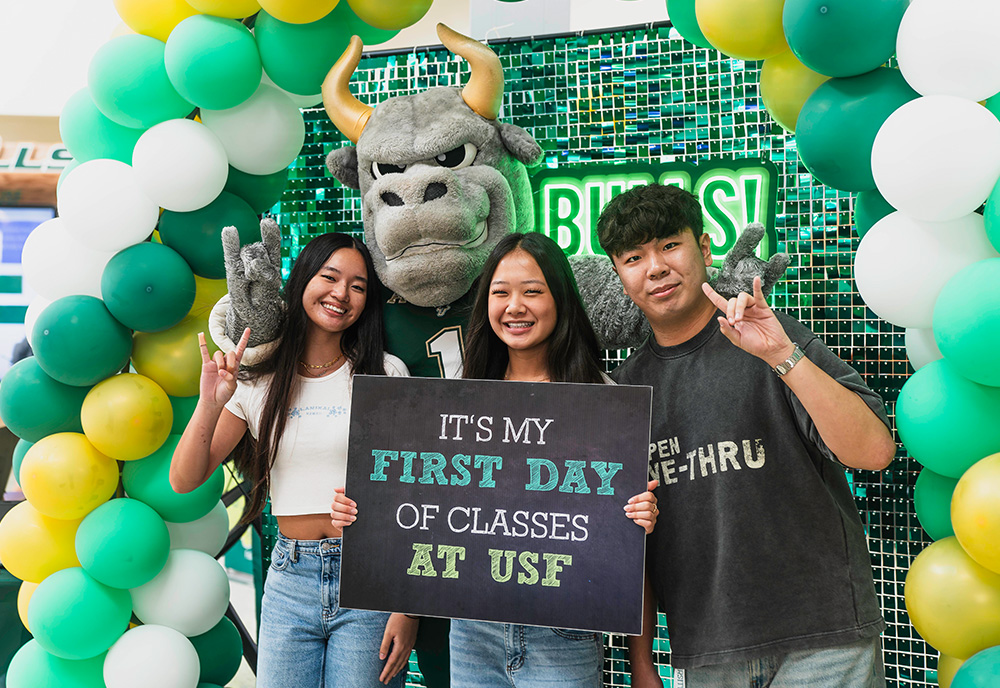 Three students stand with Rocky the Bull 