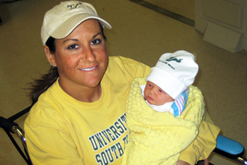 Mother holds infant son wearing USF clothing