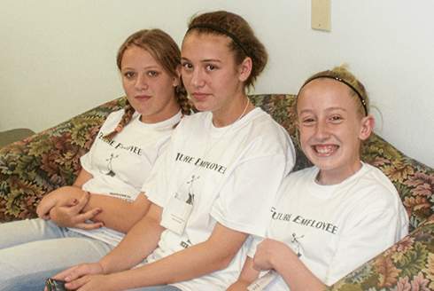 Three girls sit on a couch wearing 