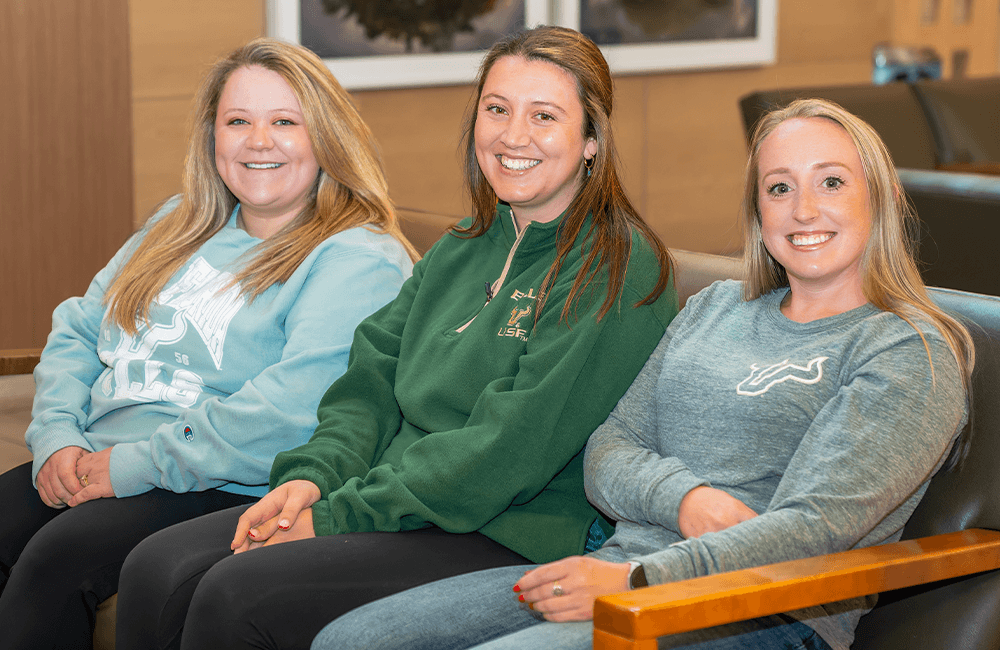 Three women sit on a couch