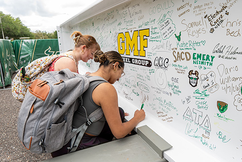 Two students sign beam