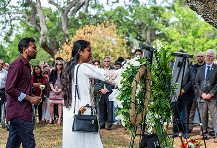 Two students place flowers near an image of one of the victims