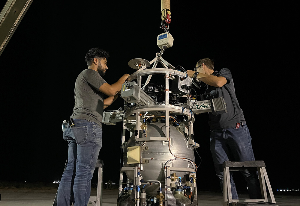 Two men work on a rocket