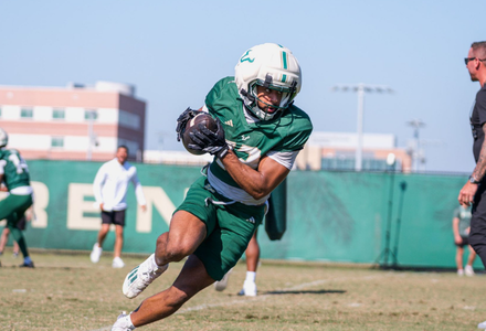 USF football player runs the ball during practice.