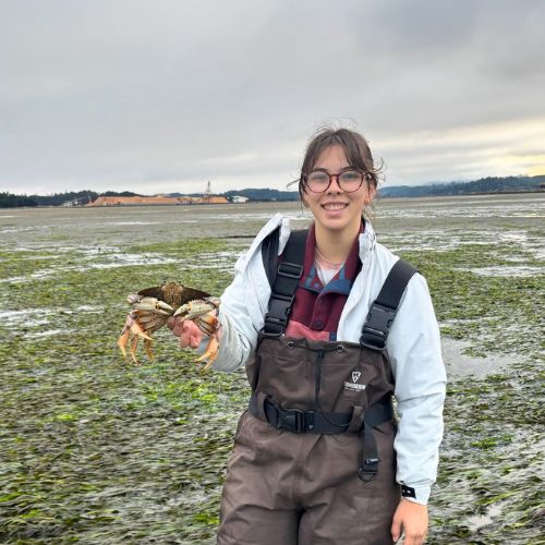 Josie Combs on her REU, holding a crab in the marsh
