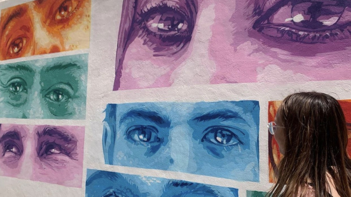 A Gilman award recipient looks at various paintings of eyes showing different states of emotion.