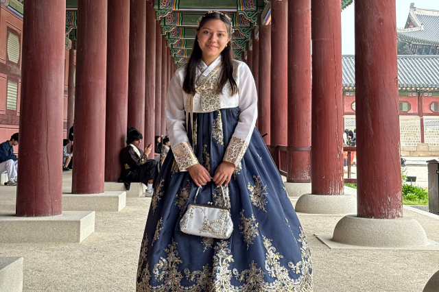 Girl standing in Korean traditional outfit in front of red columns