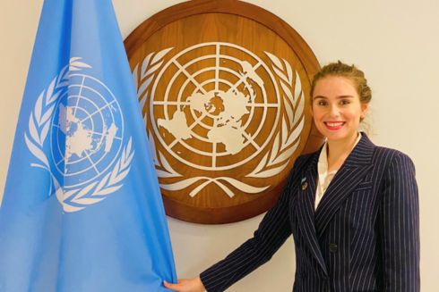 Adelitta Stanton standing next to United Nations flag and wall art piece.