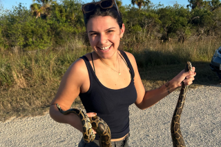 Ella Geuedouar holding a snake and smiling