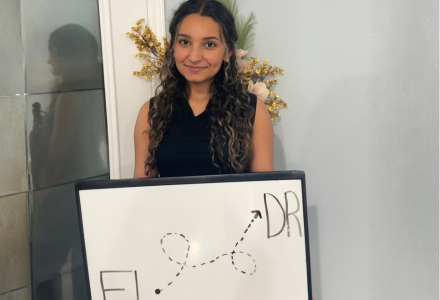 Student holding white board depicting the travel from Florida to the Dominican Republic