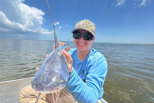 Coen McGarrah holding a baby shark on a boat in the water.