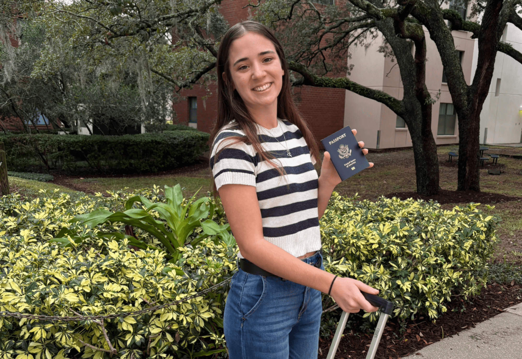 student holding suitcase and passport on USF campus