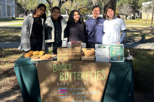 Five women stand behind bake sale table raising money