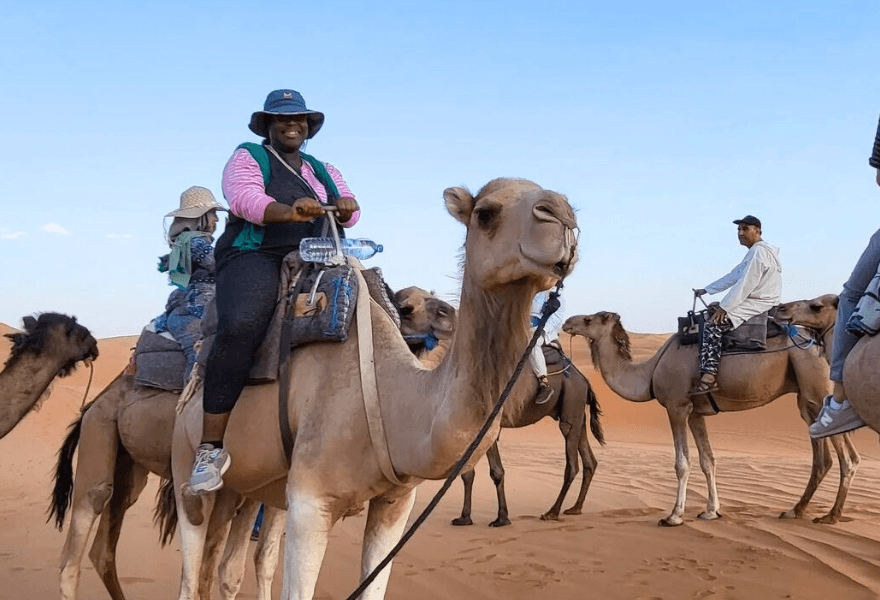 Student riding camel in the desert