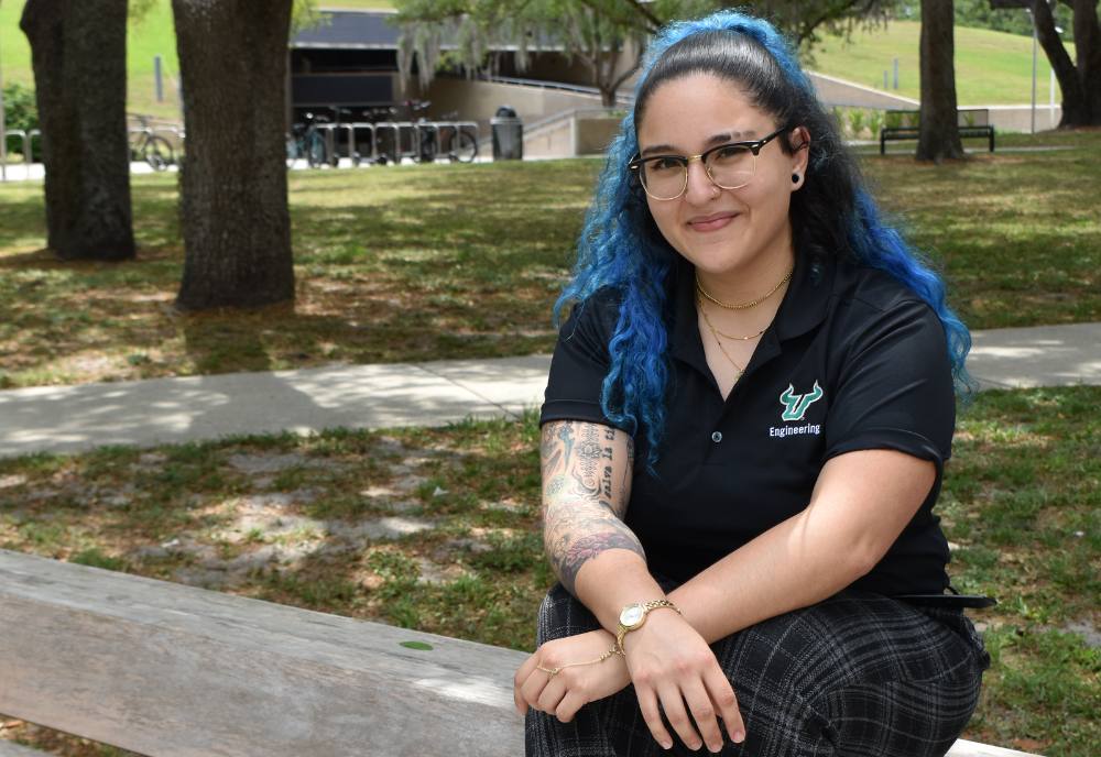 Daniela Zamora Alviarez sitting outside on a bench with her arms crossed