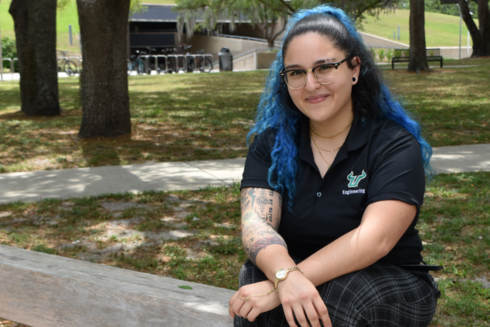 Daniela Zamora Alviarez sitting outside on a bench with her arms crossed
