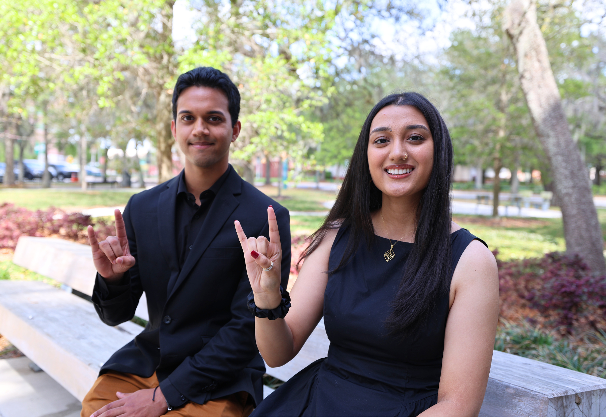 Caleb Fernandes and Diya Upadhyaya show their bull spirit on a bench outside the Judy Genshaft Honors College