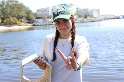 USF student Mckenzie Newbern stands on Bayboro Harbor holding an oyster brick and doing the 