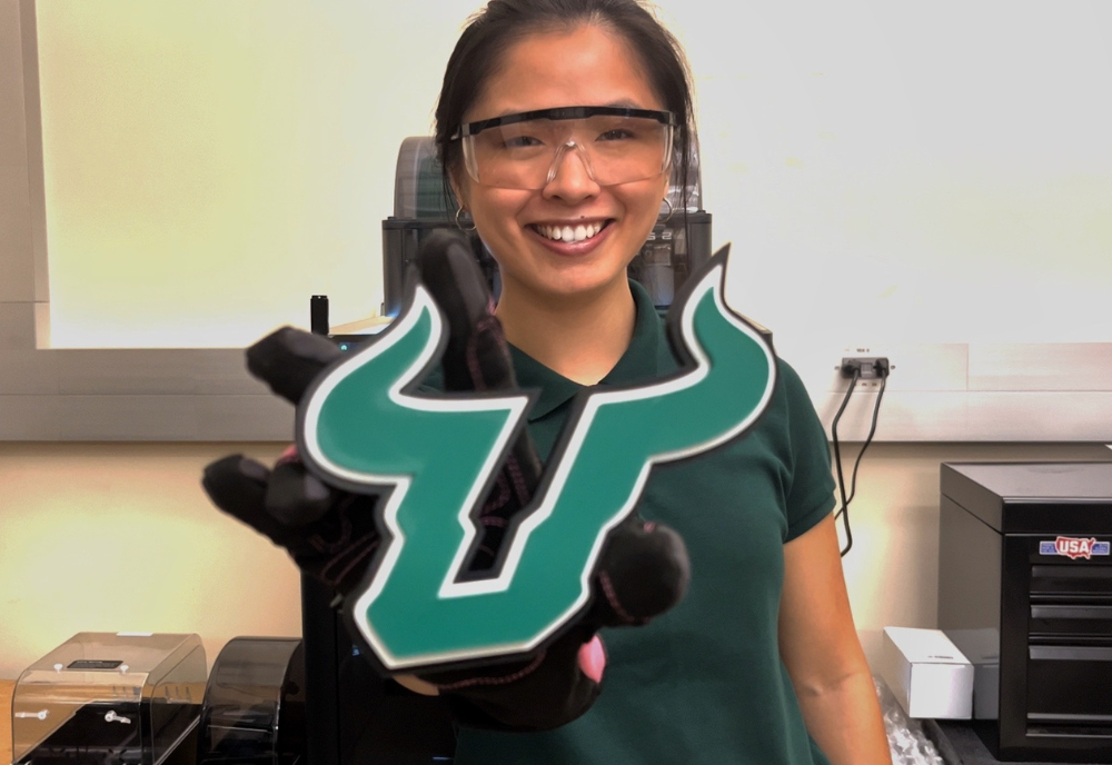 USF student Brinley Jordan holding up a USF bulls logo in a lab.
