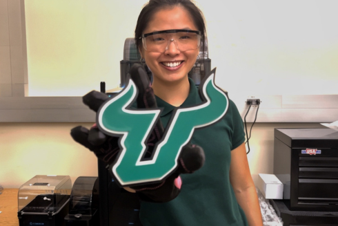 USF student Brinley Jordan holding up a USF bulls logo in a lab.