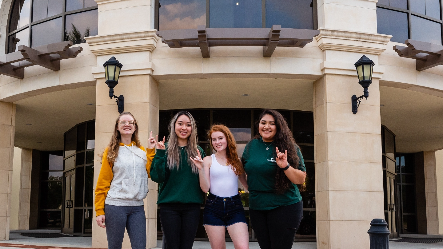 Four USF students holding up the bulls sign.