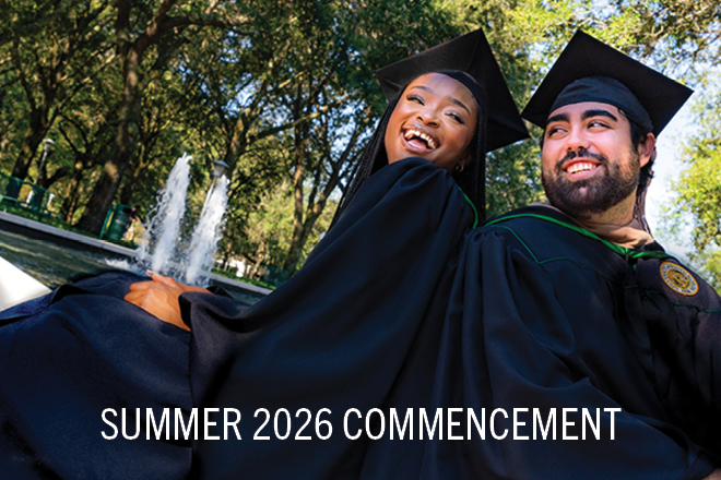 2 USF graduates smiling in their caps and gowns
