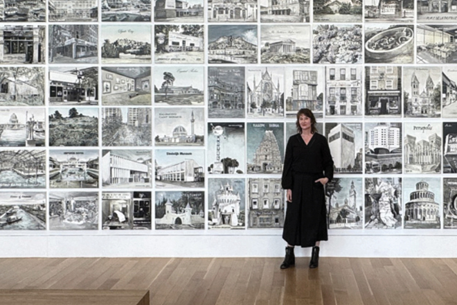 Ellen Harvey standing in front of a wall of artwork