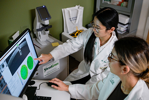people in white coats looking at health imaging scans on a computer