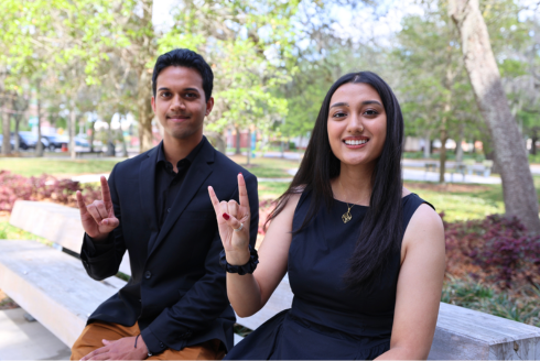 Caleb Fernandes and Diya Upadhyaya show their bull spirit on a bench outside the Judy Genshaft Honors College
