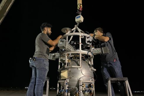 Two men work on a rocket