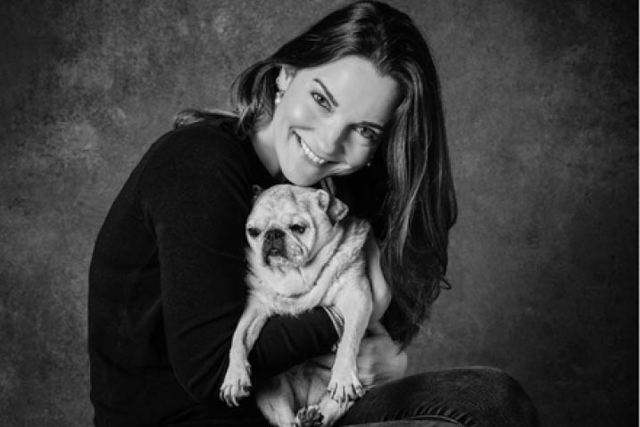 A black and white portrait of Kate Heath with her pug Ivy